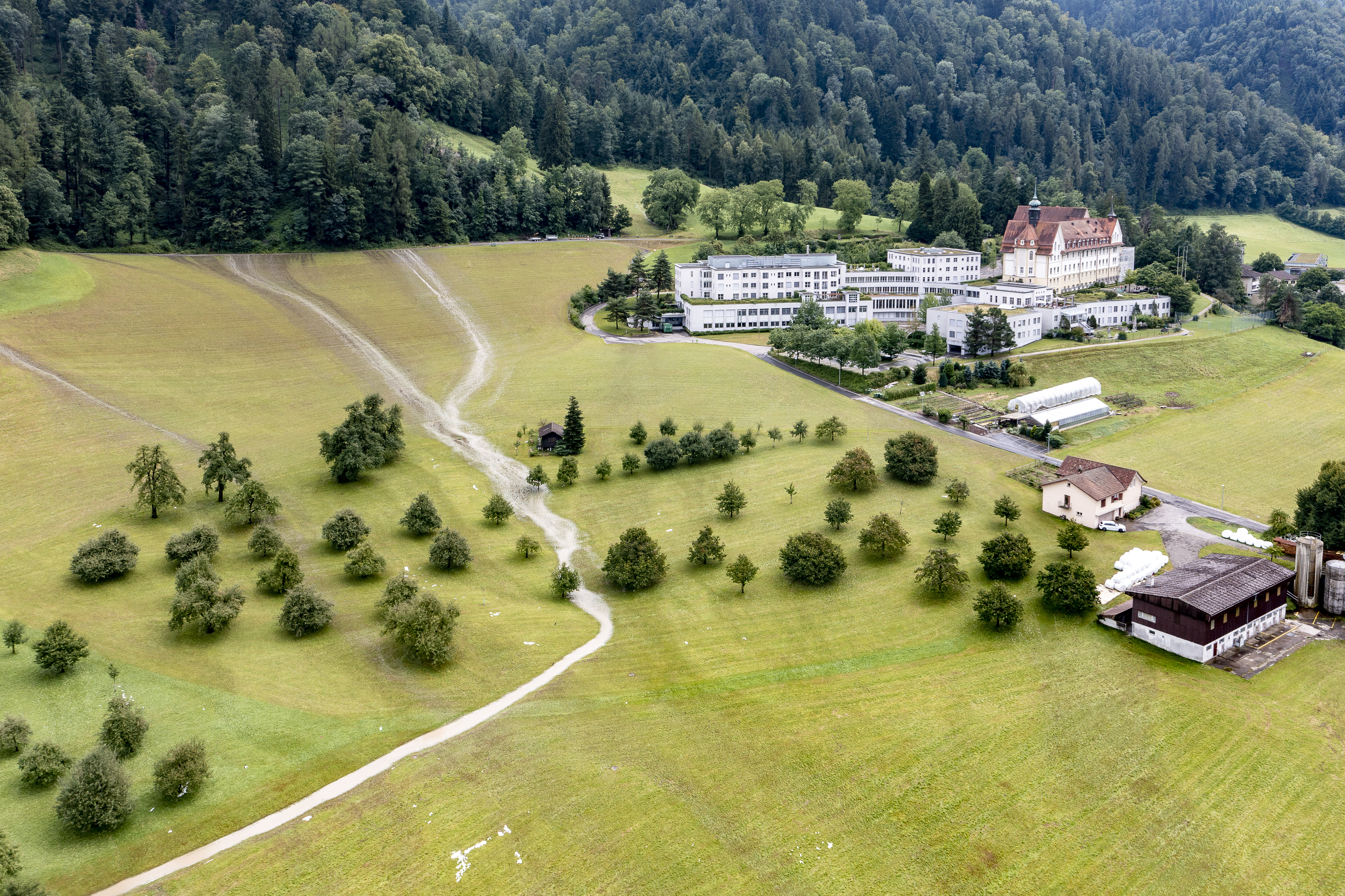 Wasser läuft neben der Klinik Zugersee vom Waldrand her über die Wiesen im Rüsli nach einem Gewitter am 25. Juli 2021